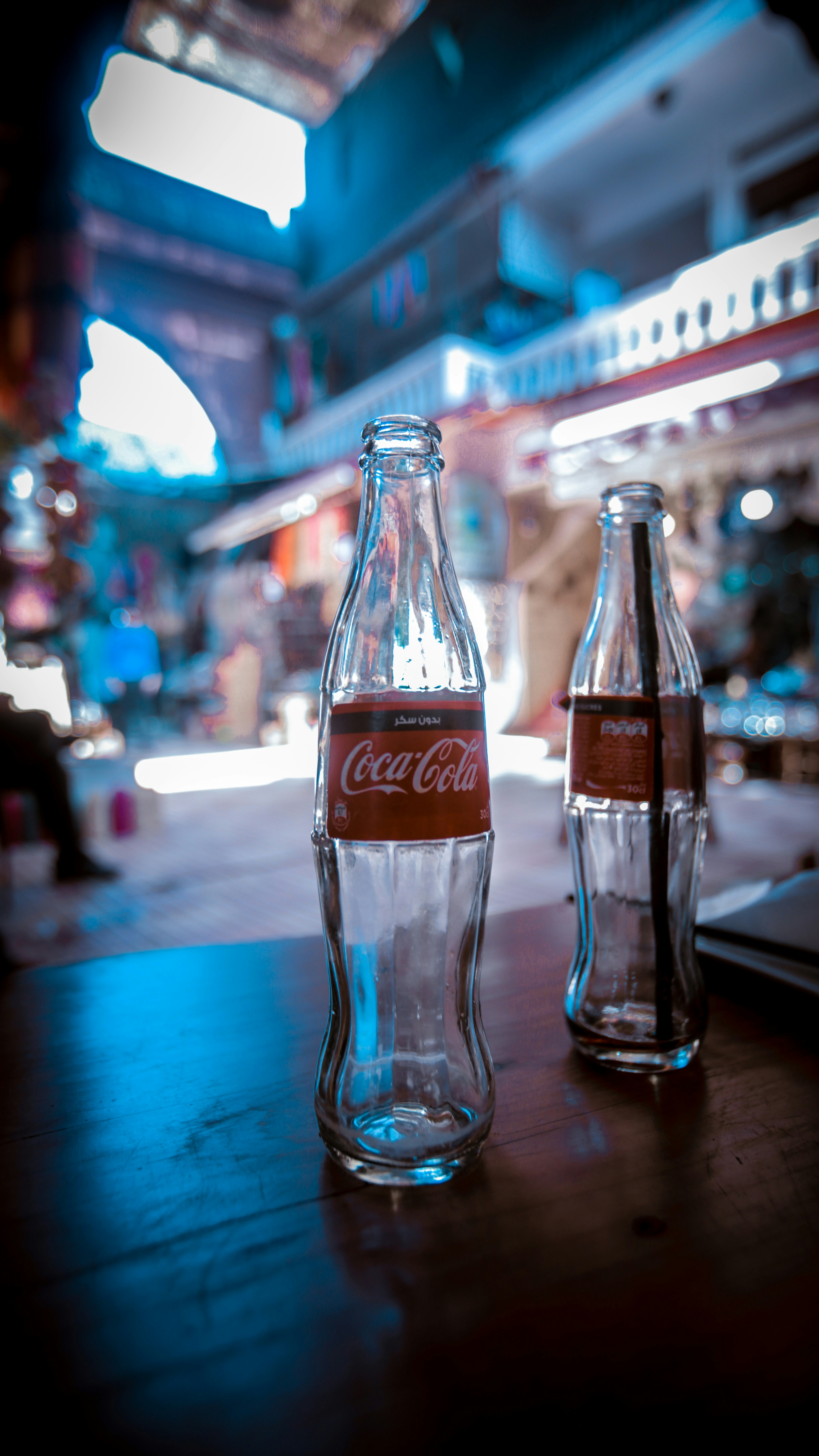 two empty Coca-Cola soda bottles on brown table